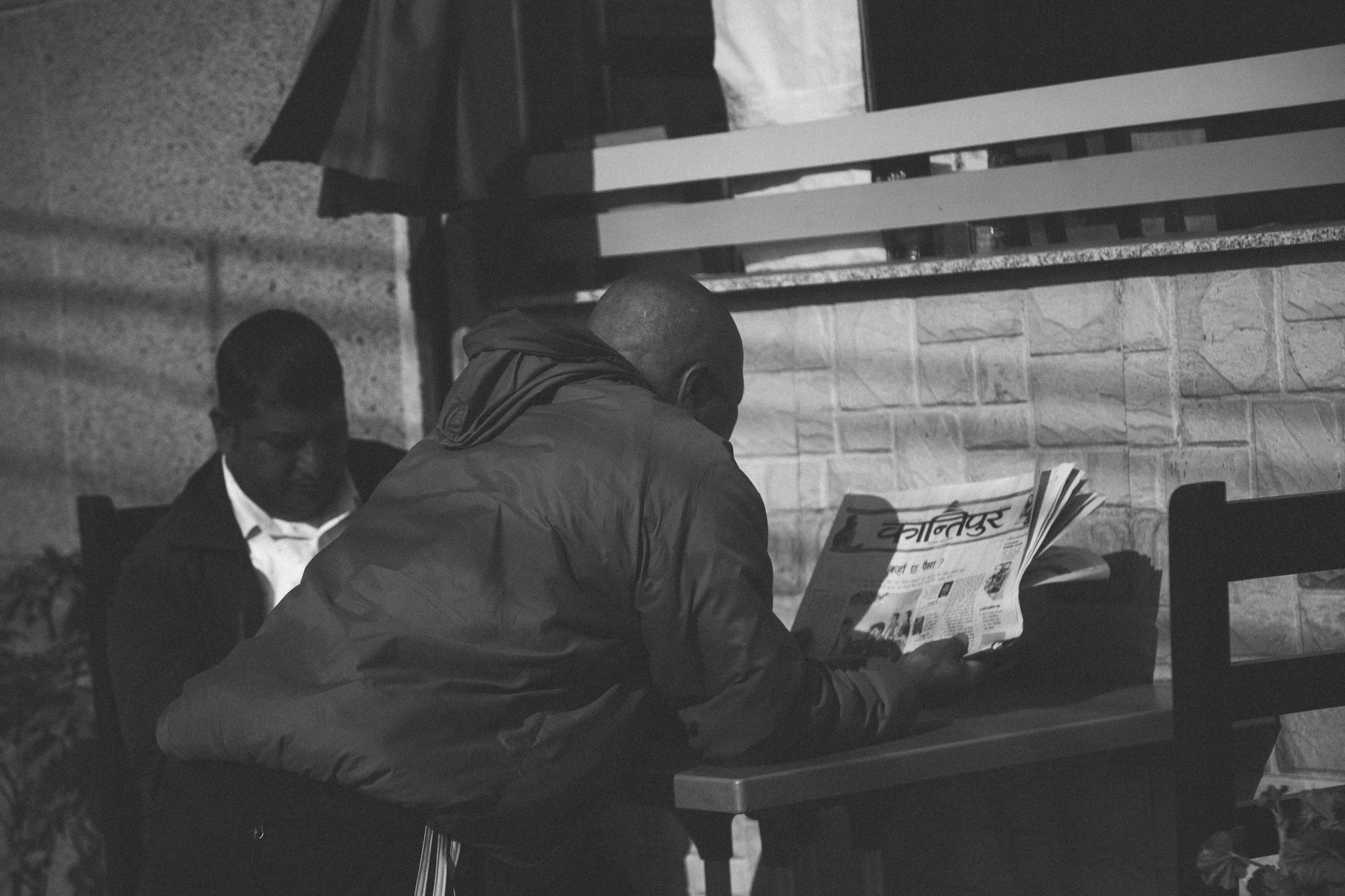 Black and white photo of a man reading a newspaper at an outdoor café in Pokhara, Nepal. — Medicare Supplement Plan N Coverag