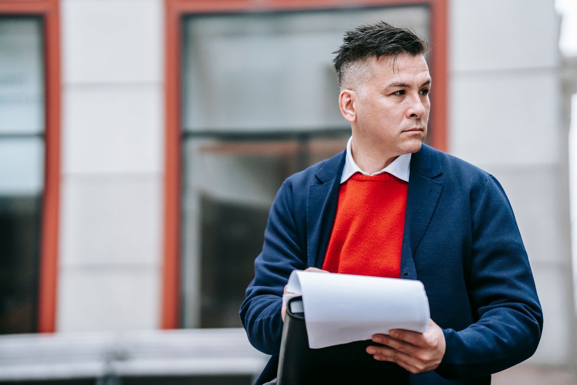 A serious man holding papers, dressed professionally in an urban environment. — Wearing your fortnite hoodie in style